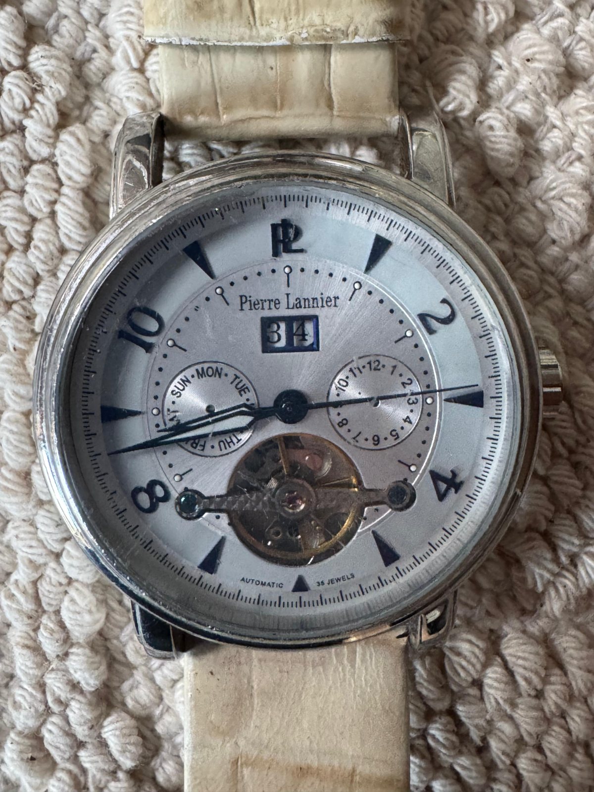 Montre automatique dont le balancier est visible sur le cadran, bracelet cuir clair