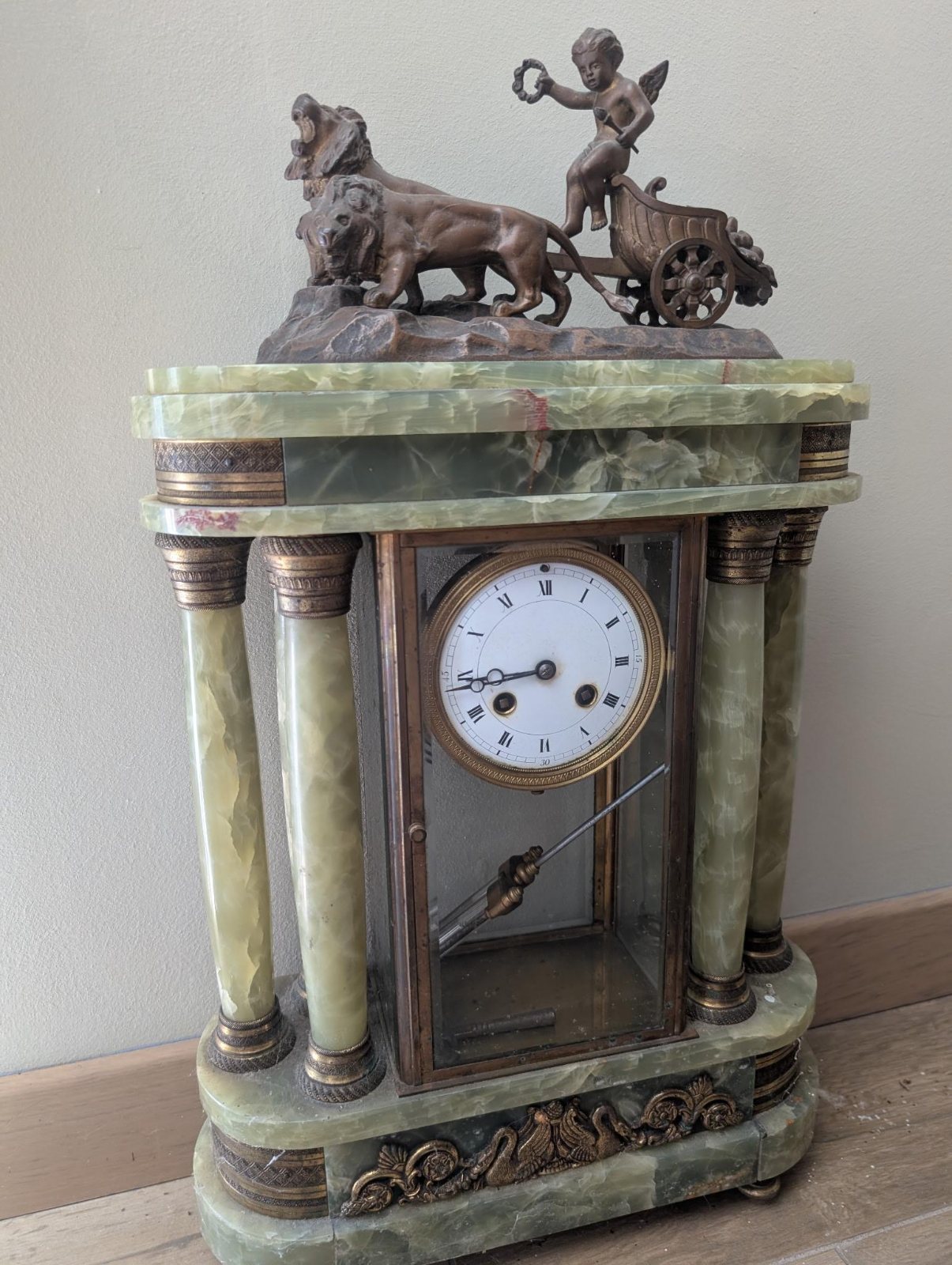Pendule de cheminée en marbre noir et marbre rouge, échappement visible derrière la vitre